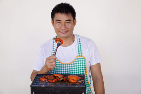 Asian man chef is cooking, grilling seafood on stove. Grilled craps. Concept, love cooking. Prepare...