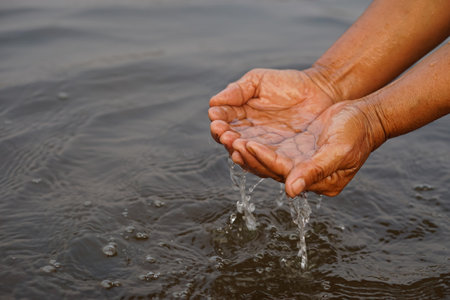 Closeup hands hold some water in river. Concept, explore, inspect clarify and quality of water from natural source. Ecology survey. Environment conservation.の写真素材