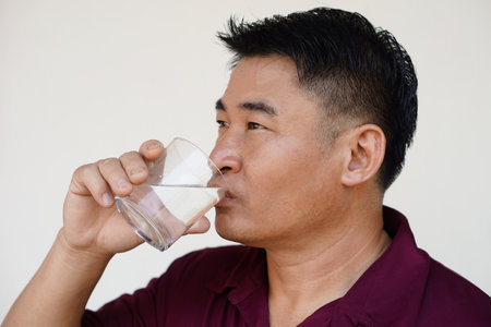 Asian man is drinking water from glass. Concept drink water for health, drink after meals, medicines , during the day or after get up in the morning. Health care, relieve thirstの写真素材