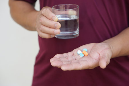 Man holds pills and glass of water to take medicine. Concept Health care, health problem, sickness and remedy. Basic self take care , treatment at home when get sick. Take pillsの写真素材