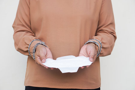Closeup woman holds sanitary pad for menstruation to put into bag before going out. Concept, female's hygienic product for period's day. Woman healthcare. Monthly intimate hygiene.の写真素材