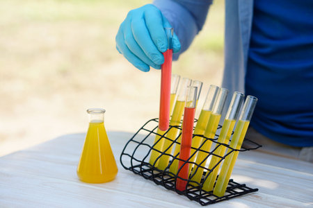 Close up hand wear blue glove holds test tube of colorful substances to do science experiment...