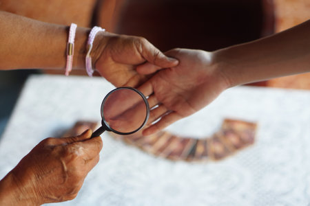 Closeup hand holds magnifying glass to inspect palm lines. Concept , palmistry, astrology. Foretelling, mystery, magic, fortune, fate. Prediction for future life ,の写真素材