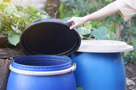 Closeup hand hold lid to cover water bucket to protect from mosquito to breed inside or other ...