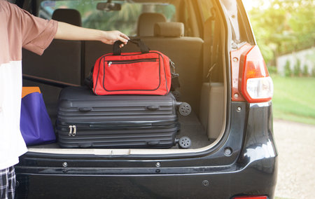 Close up man holds his suitcases  into his car. Concept, prepare for travelling. Vacation, holiday or weekend trip. Prepare and ready go.の写真素材