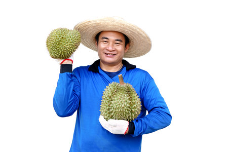 Handsome Asian man gardener wears hat, blue shirt, holds durian fruit . Concept, agriculture occupation. Thai farmers grow durian fruits as economic and export fruits productionの写真素材