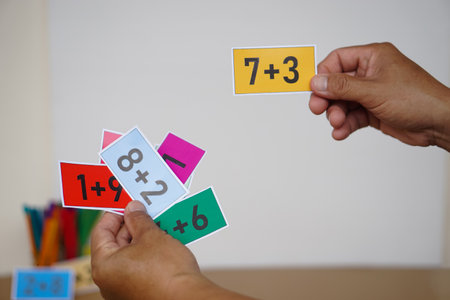 Closeup teacher hand hold paper cards with numbers addition, plus for teaching Math subject. Concept, Education, Teaching aid, materials for kids. Education, Practice calculateの写真素材