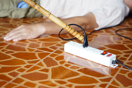 Using wooden stick is moving away the electric plug socket from the unconscious man who lay down on...