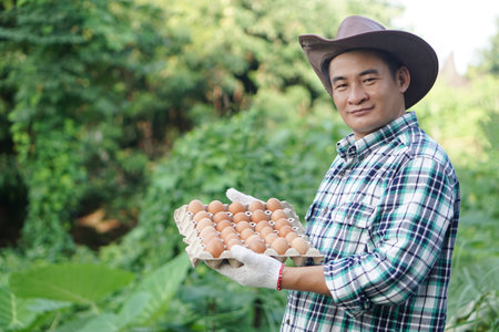 Handsome Asian man farmer holds tray of eggs at garden. Concept, Organic agricultural farming, Farmers produce healthy eco food. Best food during bad economy. Delivery to home.の写真素材