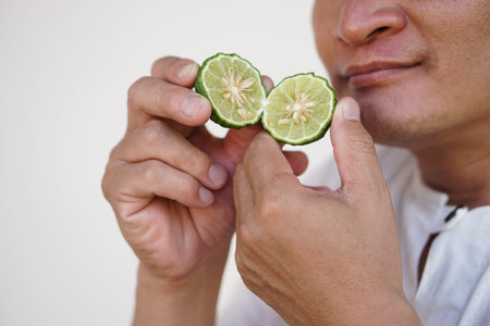 Closeup man holds half cut kaffir lime fruit to smell.  Concept, herbal fruit, aromatherapy, Kaffir...