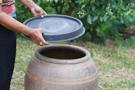 Closeup hands hold lid to cover water jar to protect from mosquitoes to breed inside or other ...