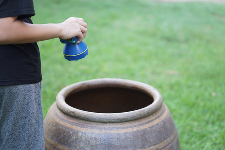 Close up boy hold flashlight to explore mosquito larvae or insects that breed inside water jar. Concept, campaign to stop mosquitoes cycle to lay eggs in water container.の写真素材