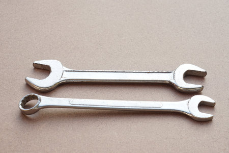 Two metal chrome wrenches or spanners  on brown background. Concept, handyman, mechanic tools. ...