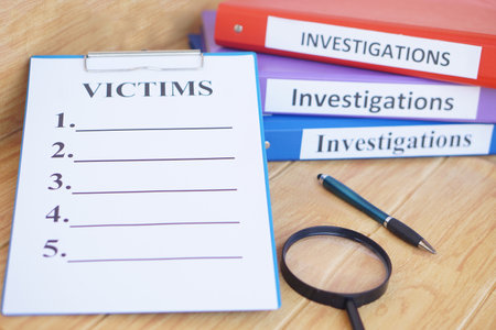 Investigation folders and victims list paper notepad clipboard. Magnifying glass and pen. Concept, crime. Analyzing criminal investigation.の写真素材