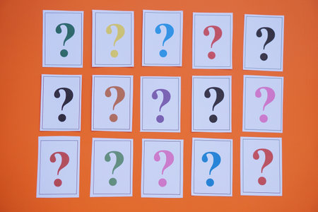 Paper cards of colorful question marks  on orange background. Concept. Teaching aid. Education materials for doing activity or playing investigation games about finding answers.の写真素材