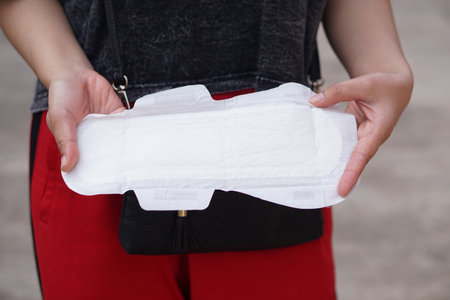 Close up woman hand is holding sanitary napkin. Concept: female's hygienic product for period's day. Menstrual pain on the day of period. Woman healthcare. Monthly intimate hygieneの写真素材