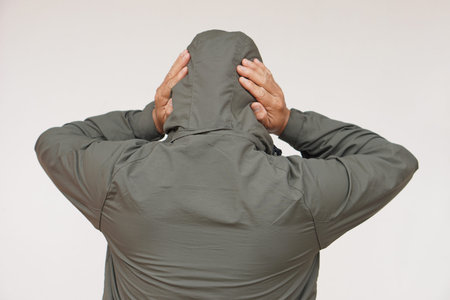 Back view of man wears hoodie, uses his hands to cover ears. Concept, don't want to listen or hear...