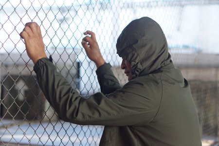 Man wears hoodie was detained in metal net cage . Concept, delinquency. Punishment....