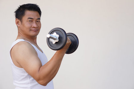 Asian man is lifting dumbbell for exercise. Concept, Exercise for health bodybuilding. Strengthen muscle. Weight lifting. Healthy lifestyle. Work out make strong of body.の写真素材