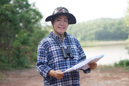 Asian woman explorer hold paper map to explore nature at forest and lake area. Concept, nature...