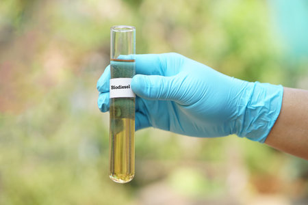 Close up hand wears blue glove holds test tube of biodiesel. Concept. Science reseach to develop...