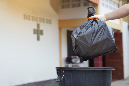 Hand holding garbage black bag putting in to the bin. Concept, garbage management, Keep clean for sanitary and community service for the best environment. Zero waste.の写真素材