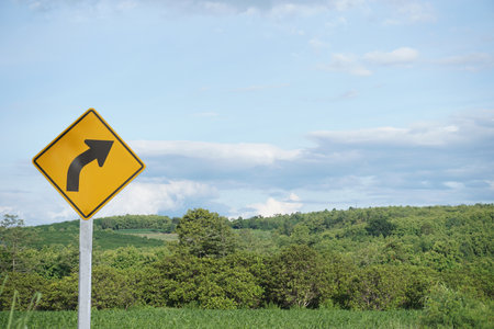 Curved road traffic yellow sign. Warning attention sign Right Winding Road. 
Concept, Warning traffic sign for  Giving direction for transportation and way to go.の写真素材