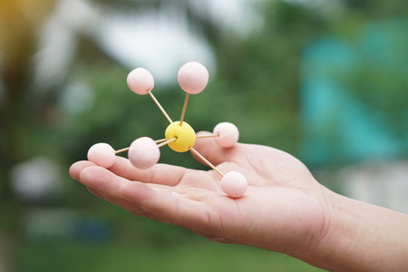 Closeup hand hold DIY molecule structure made from toothpicks and plasticine. Concept, teaching aids, educational materials. science lesson about molecule. Creative task from learnの写真素材