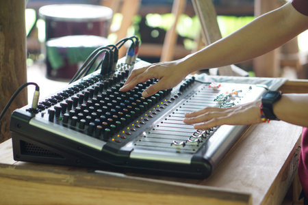 Close up hands are adjusting audio mixer or sound mixer controller machine. Concept, sound controler equipment for Dj or musicians to control level of different sound for entertainの写真素材