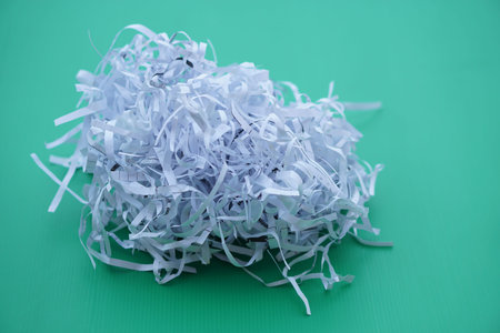 Pile of sliced used paper to be small stripes, prepare to recycle process on green background....
