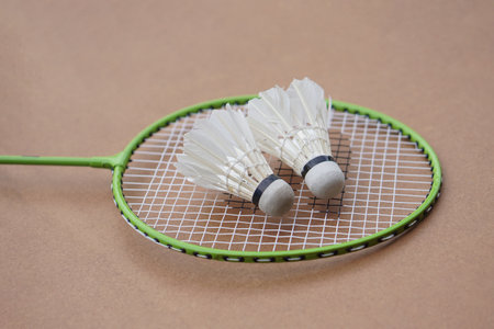 Shuttlecocks and rackets. Badminton sport equipments on brown background. Concept, sport, exercise, recreation activity for good health. Popular sport for all gendersの写真素材