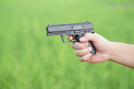 Hand hold black pistol gun to shoot. Concept, dangerous violent weapon, use for self protecting, killing, destroying or threatening in crime. Handgun.の写真素材