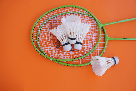 Shuttlecock and rackets. Badminton sport equipment on orange background. Concept, sport, exercise, recreation activity for good health. Popular sport for all gendersの写真素材