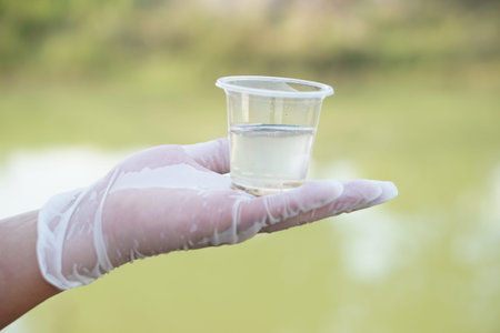 Close up hand hold glass that contains sample of water to do experiment. Concept Testing of water...