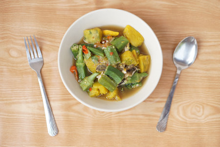 Bowl of curry mixed organic okra , pumpkin and Thai herbal ingredient. Spoon and fork. Concept, local food with nutrient. Healthy eating. High fiber and vitamin. Top view shotの写真素材