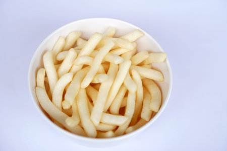 Crispy potato sticks served in a simple white cup. Popular crunchy snack loved by kids and adults...