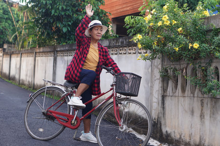 Senior Asian woman riding a vintage bicycle outdoors. Healthy lifestyle concept, active aging, leisure activity, casual fashion, enjoying freedom and independence in everyday life.の写真素材