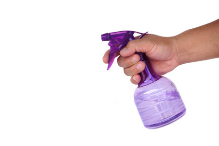 Man hand holding transparent purple spray bottle isolated on white background. Household cleaning...