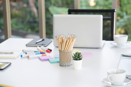 Pencils in the basket on the desk with a computer