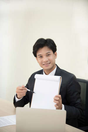 A young Asian businessman showing a blank papeの写真素材