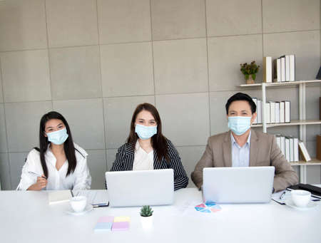 Asian office workers wear face masks at corporate meetings to prevent thevirus, or , ideas for a new normal lifestyle in the workplace. Awareness of wearing masksの写真素材