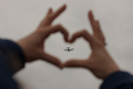 Airplane in the hands heart on the grey background, love travelling, romantic.の写真素材