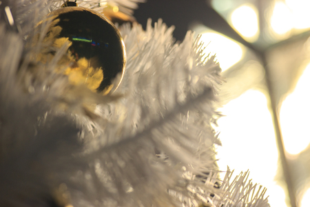 Gold ball on a white Christmas tree, decorations for new year and Christmas. Cozy home, preparing for fun. Background for greeting cardsの写真素材