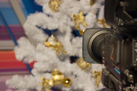 shoot video camera white Christmas tree with gold ornaments. pink background. Christmas shooting, festive mood. videographer's workの写真素材