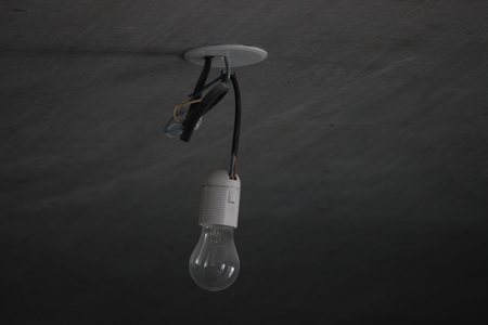 incandescent bulb in cartridge against gray concrete wall. energy saving, environmental care. economical use of electricity.の写真素材