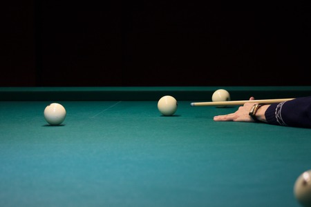 man playing Russian Billiards. hand holds the cue and has the ball on the green background of the table. put the ball in pocket, win the game. rest, Hobbies, competitions.の写真素材