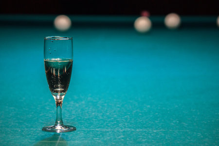 glass of champagne is on the pool table. the winner of the game, the champion drinks a glass of sparkling wine. Hobbies, sports, passionate people.の写真素材