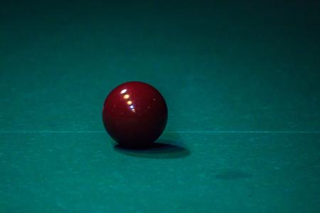 maroon ball lying on a green pool table. time before the game. the reflection of the lamp in the bowlの写真素材