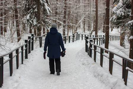 person walking on snow-covered road in the woods. winter frosty weather. people are dressed in warm clothes.の写真素材