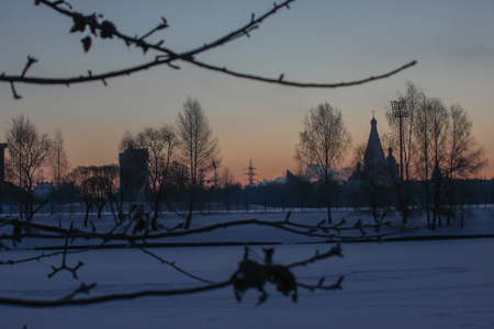 branches with frost on background of the city dawn. bright winter morning. the bright scarlet sun rises on the horizon from houses and churches. clear frosty weather in the streetの写真素材